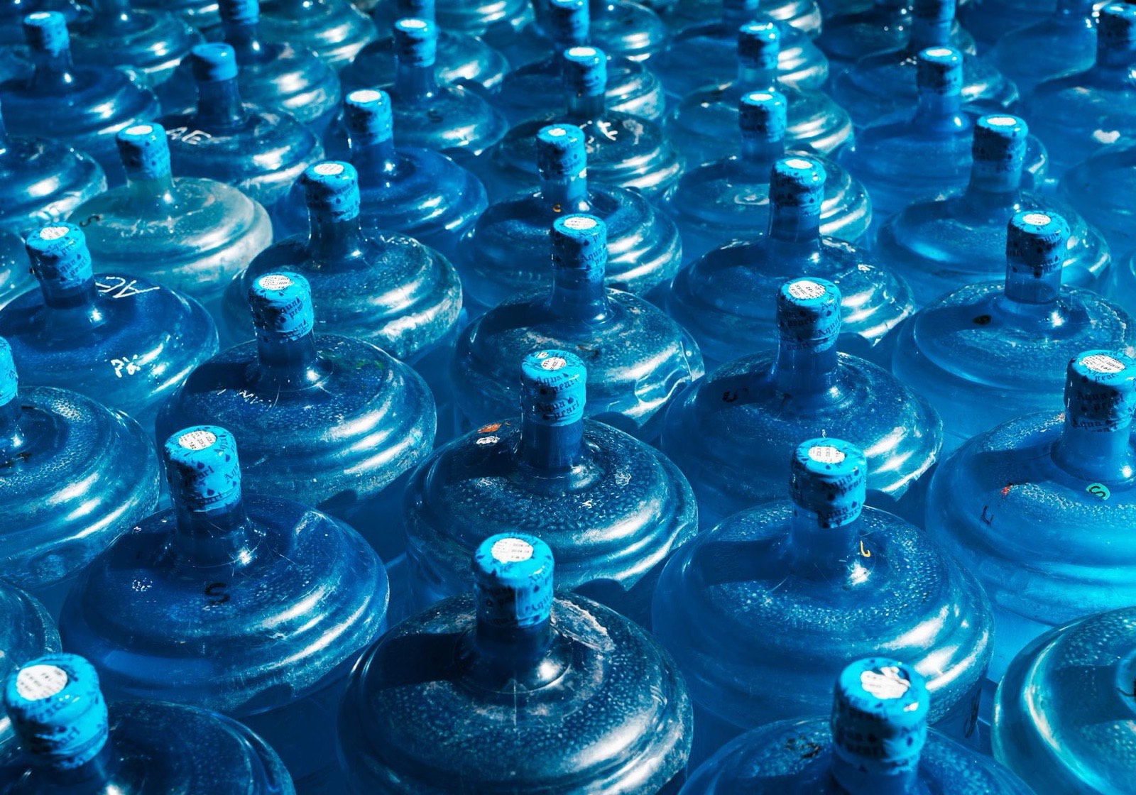 Rows of sealed blue 20-litre drinking water bottles